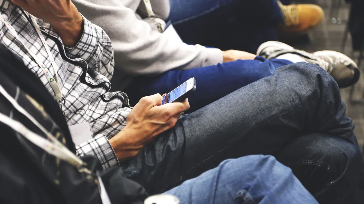 Bir etkinlikte yan yana oturan ve telefon kullanan katılımcılar