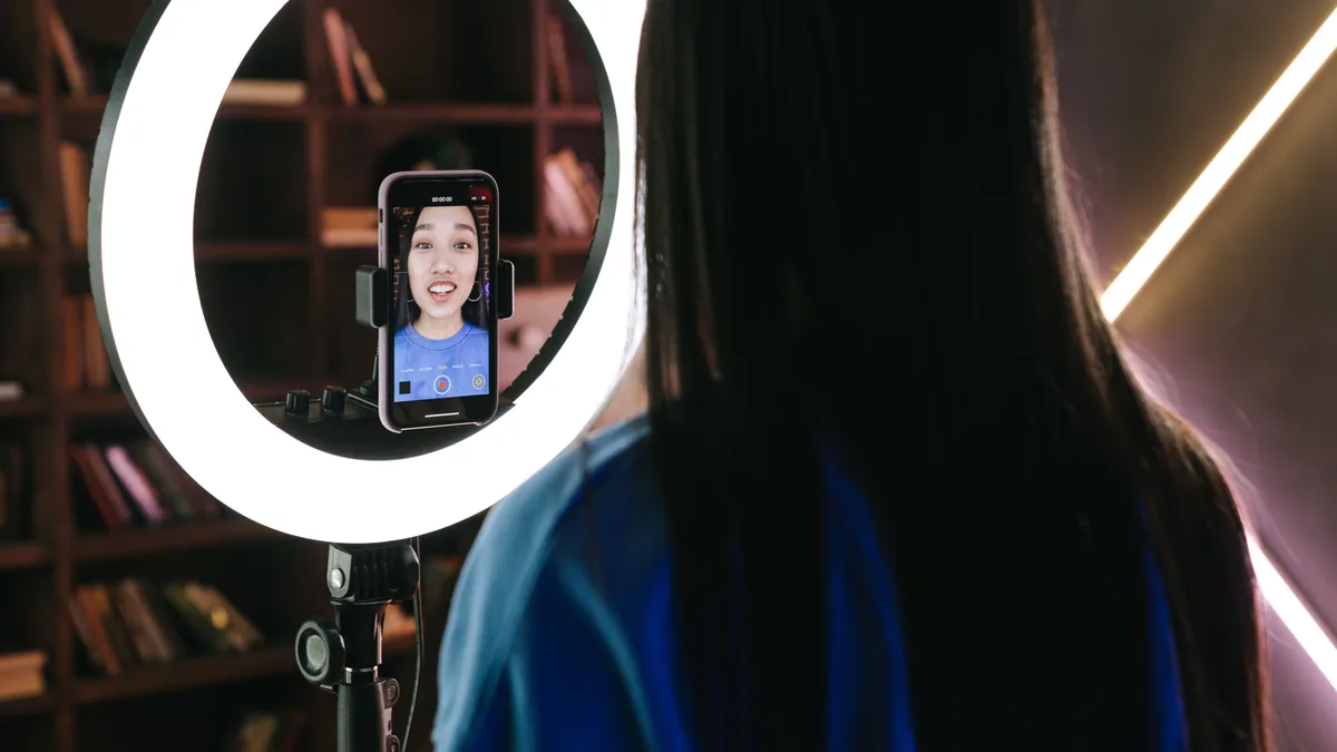 Tripod üzerindeki telefonla dış mekânda çekim hazırlayan kadın