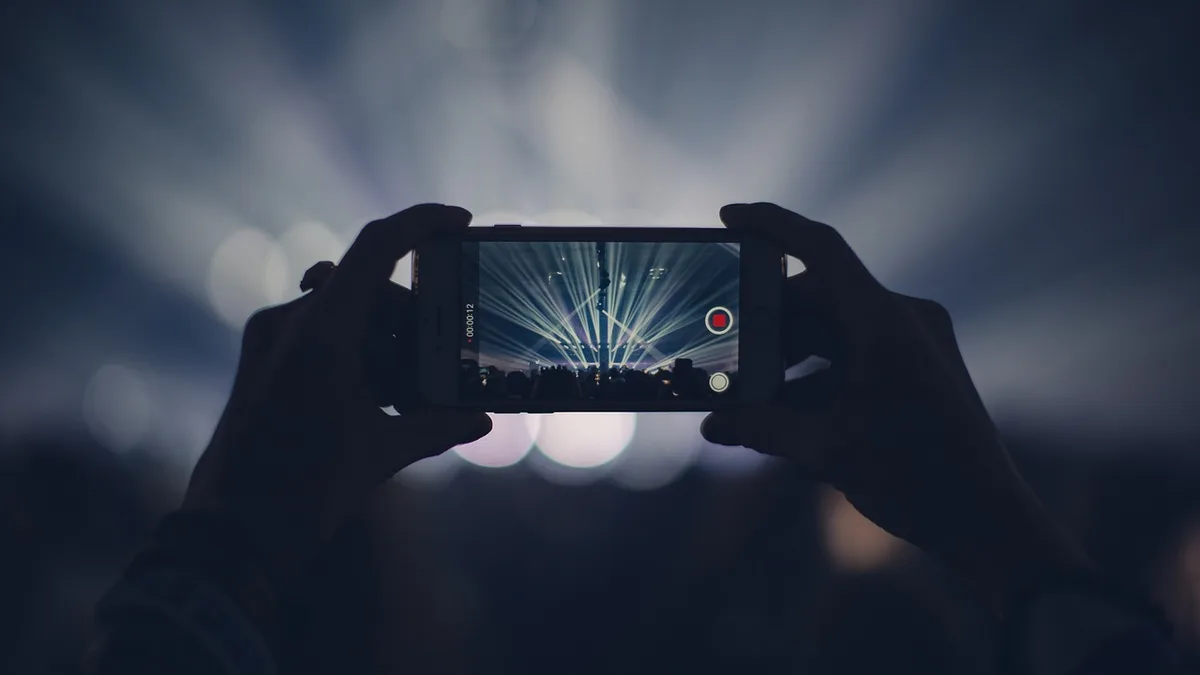 Konser ışıklarını telefon ekranından kaydeden eller