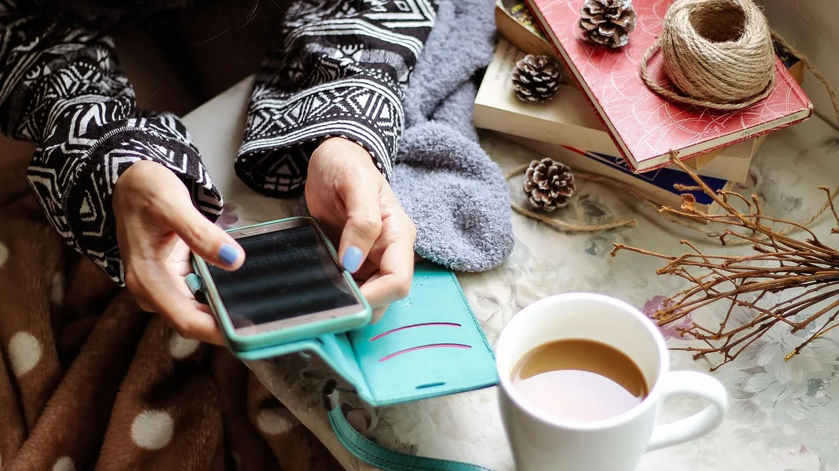 Kahve yanında telefon ekranına bakan kişi