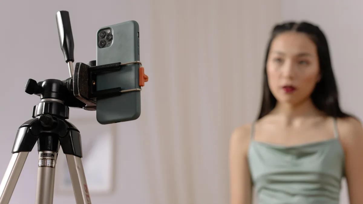 Tripod üzerindeki telefon kamerası önünde oturan kişi