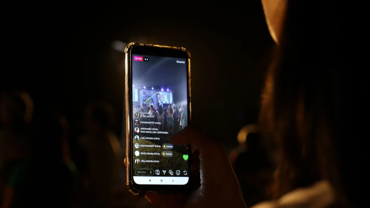 Telefonda canlı performans izleyen kişinin eli