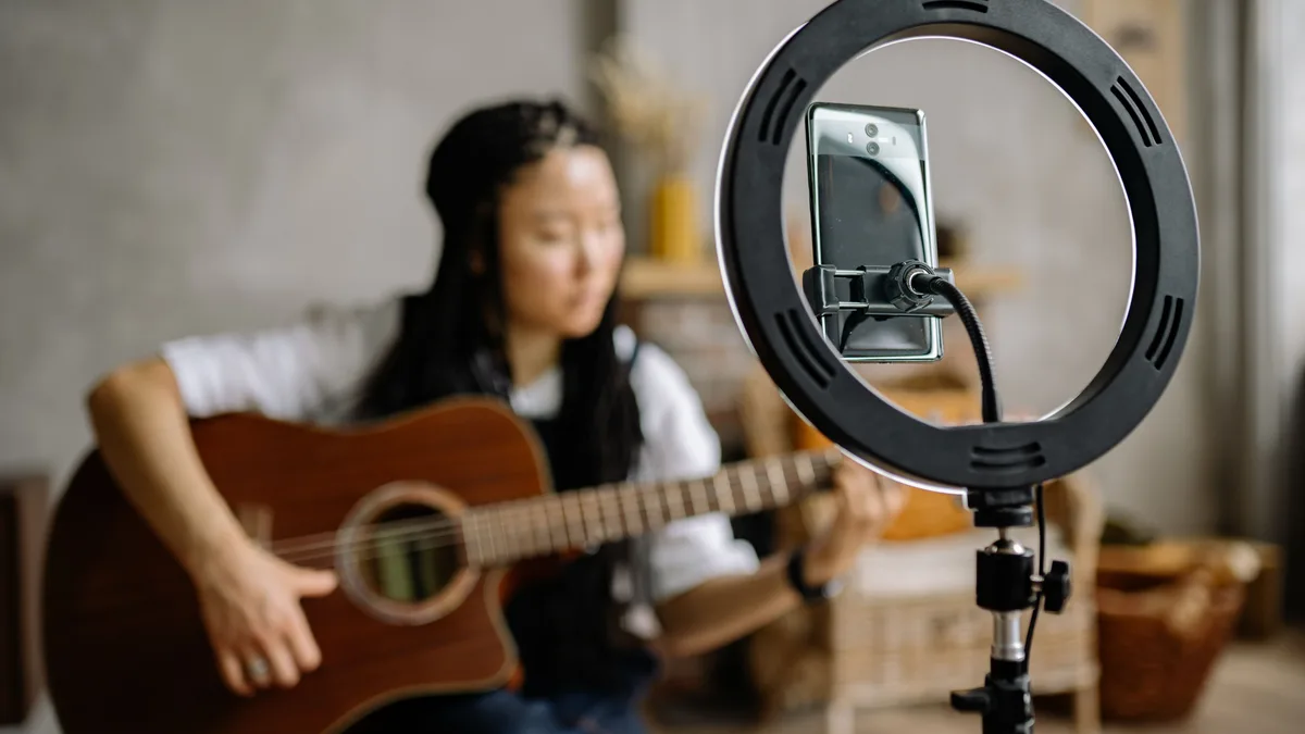 Halka ışık ve telefon karşısında gitar çalan kadın