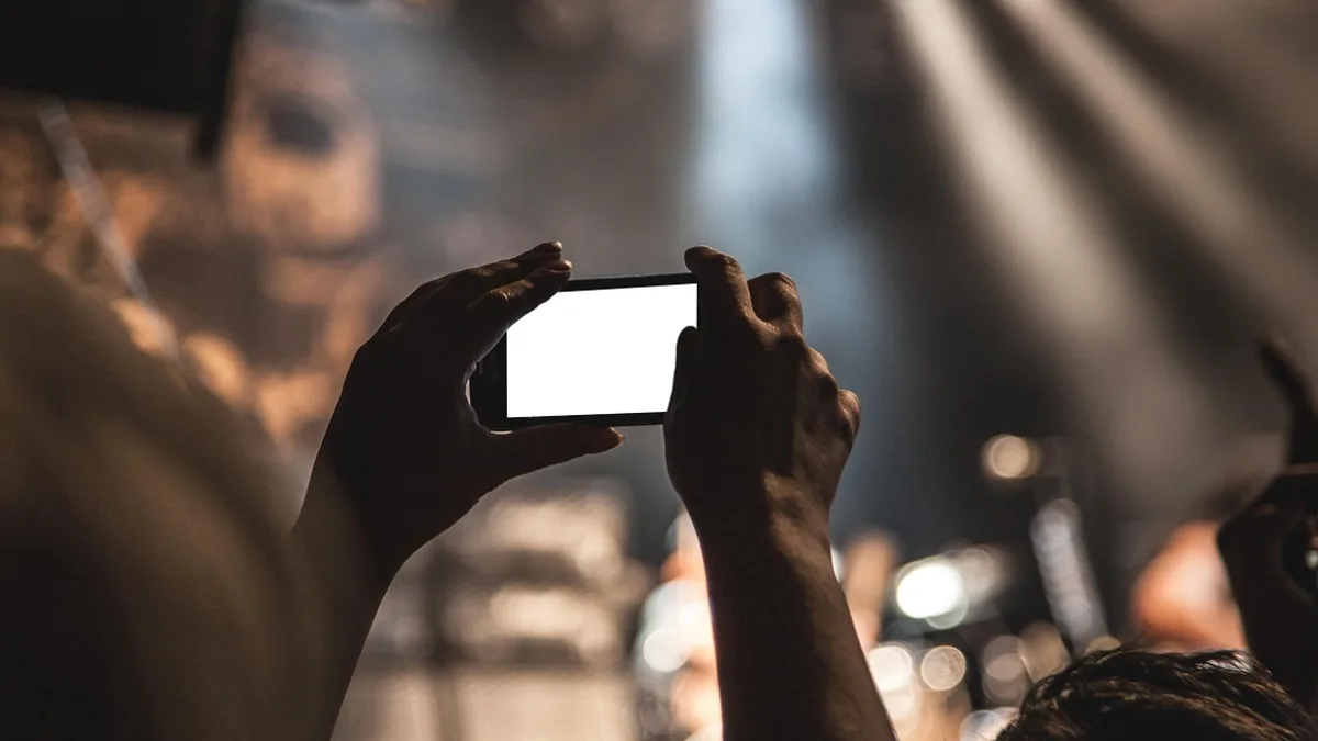 Kalabalık ortamda telefonu yatay tutarak kayıt yapan kişi