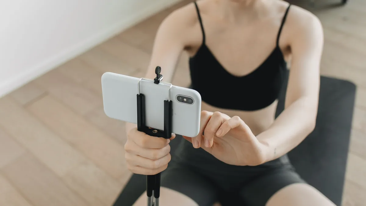 Evde yoga videosu için telefonu tripoda yerleştiren kadın