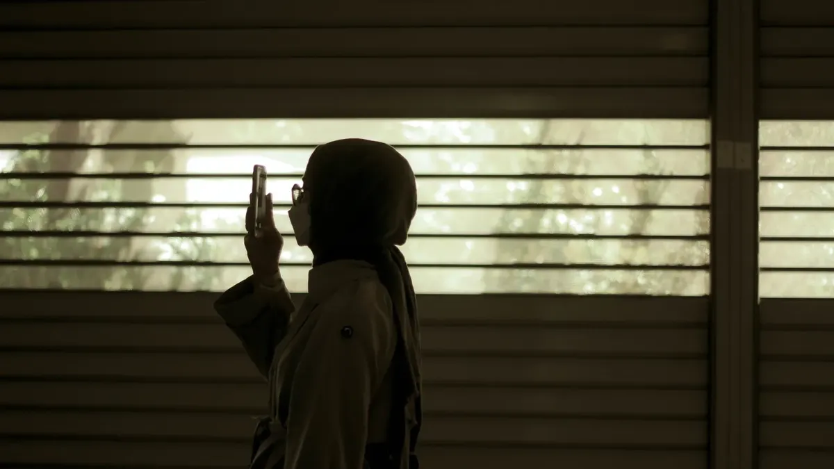 Pencere yanında akıllı telefon kullanan siluet
