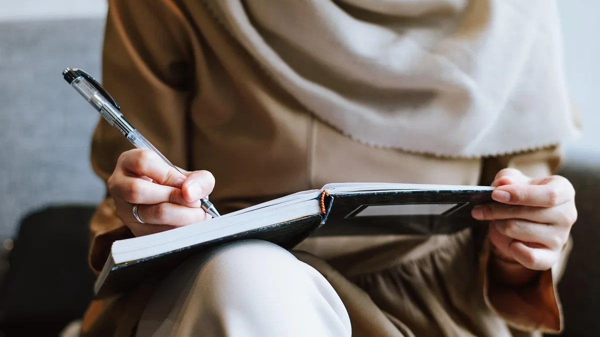 Not defterine yazı yazan ve tablet tutan kişi