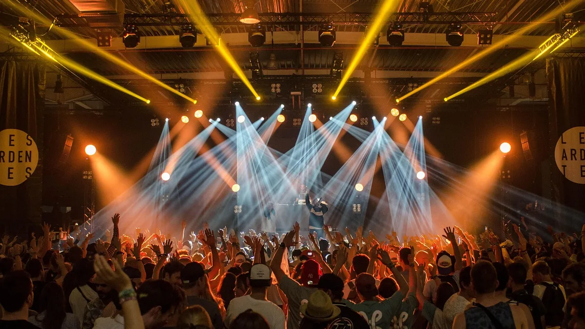Sahne ışıkları altında konser izleyen kalabalık