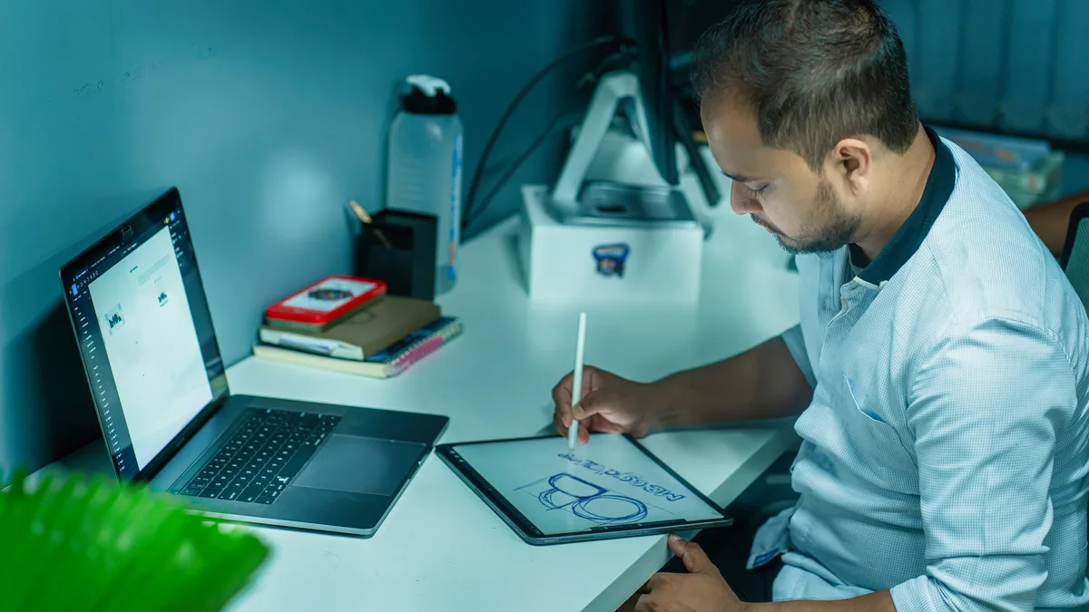 Masa başında grafik tablet üzerinde çizim yapan tasarımcı