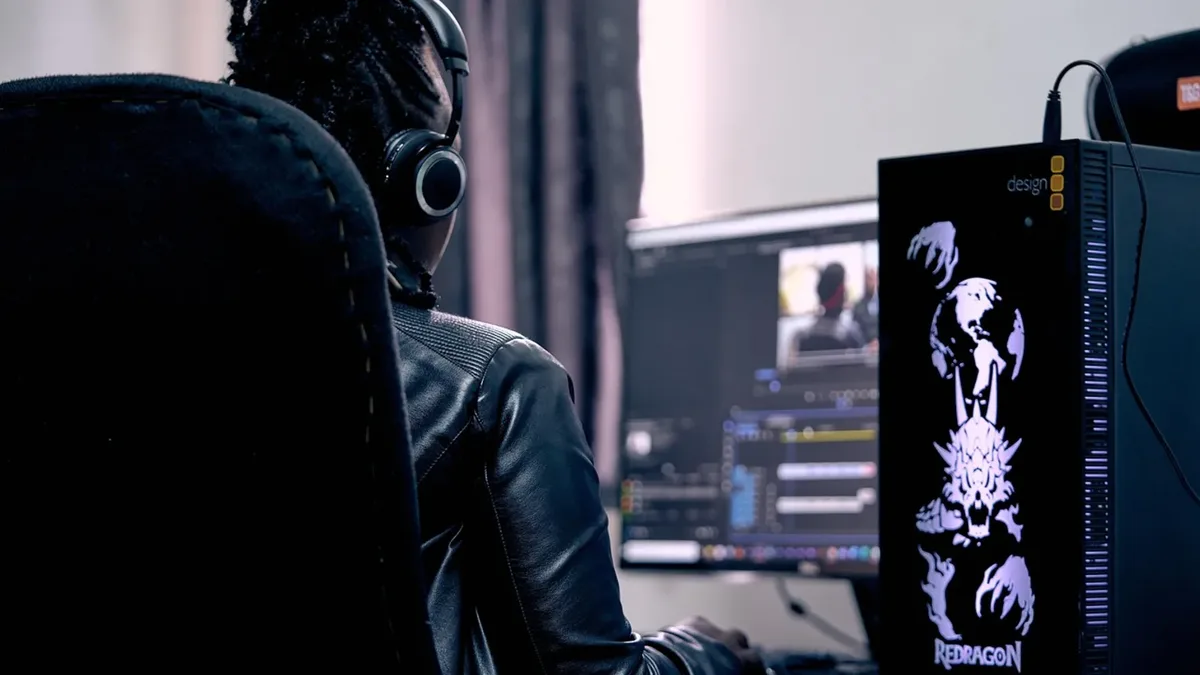 İki monitörde video kurgusu yapan kulaklıklı kişi