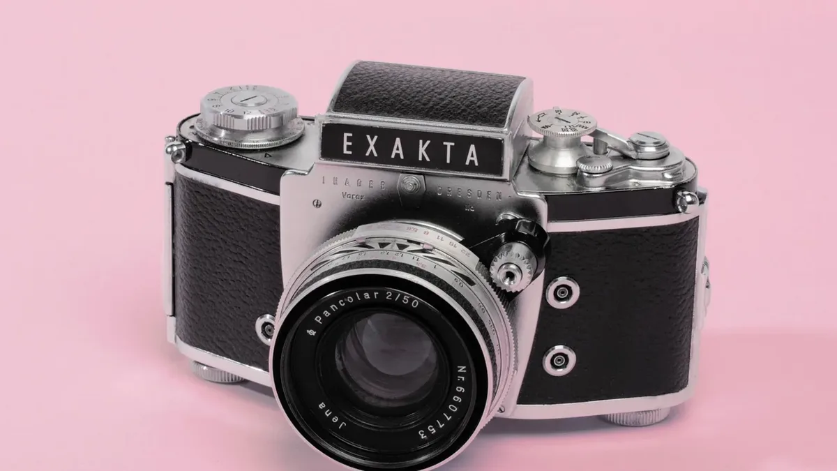 Pembe fonda stüdyo ışığıyla çekilmiş analog fotoğraf makinesi
