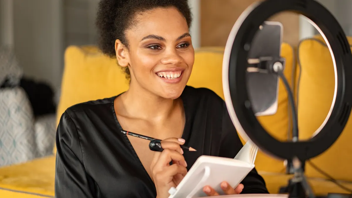 Ring light önünde defterine bakarak kayıt yapan içerik üreticisi