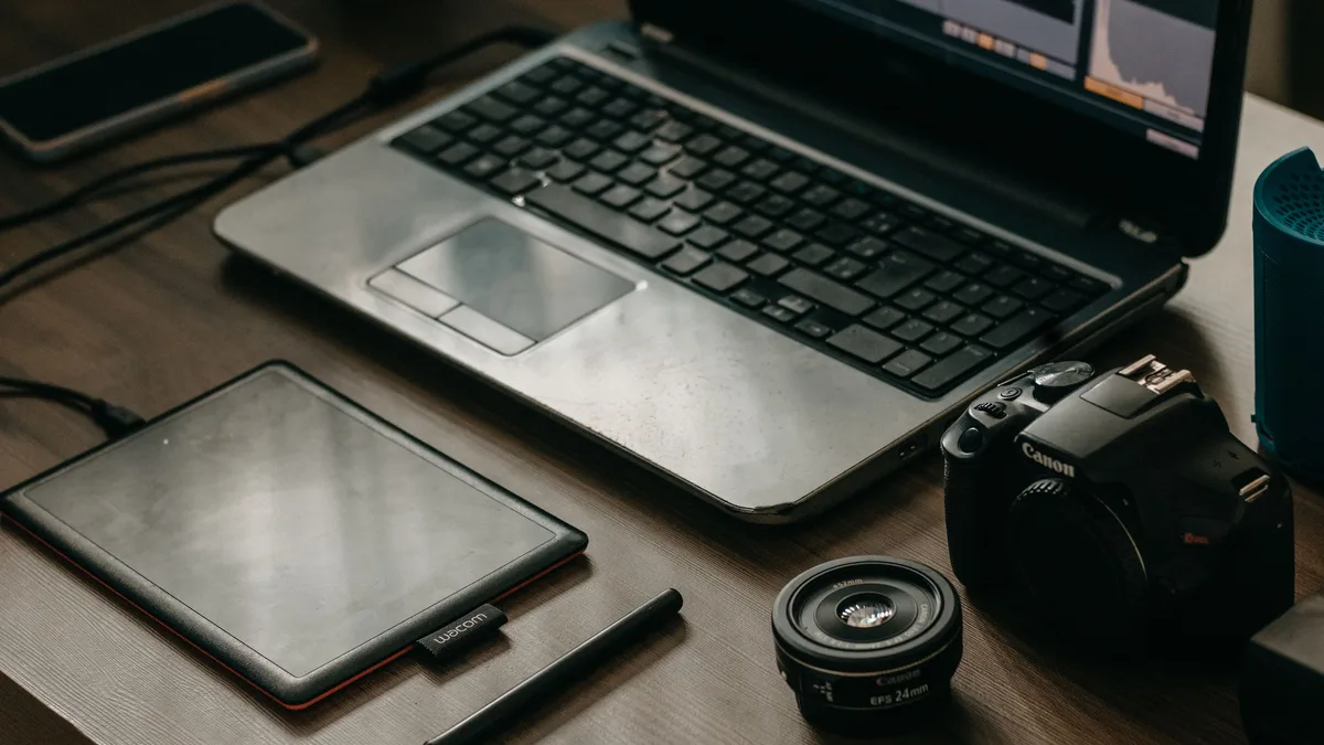 Dizüstü bilgisayar, fotoğraf makinesi ve grafik tablet bulunan çalışma masası