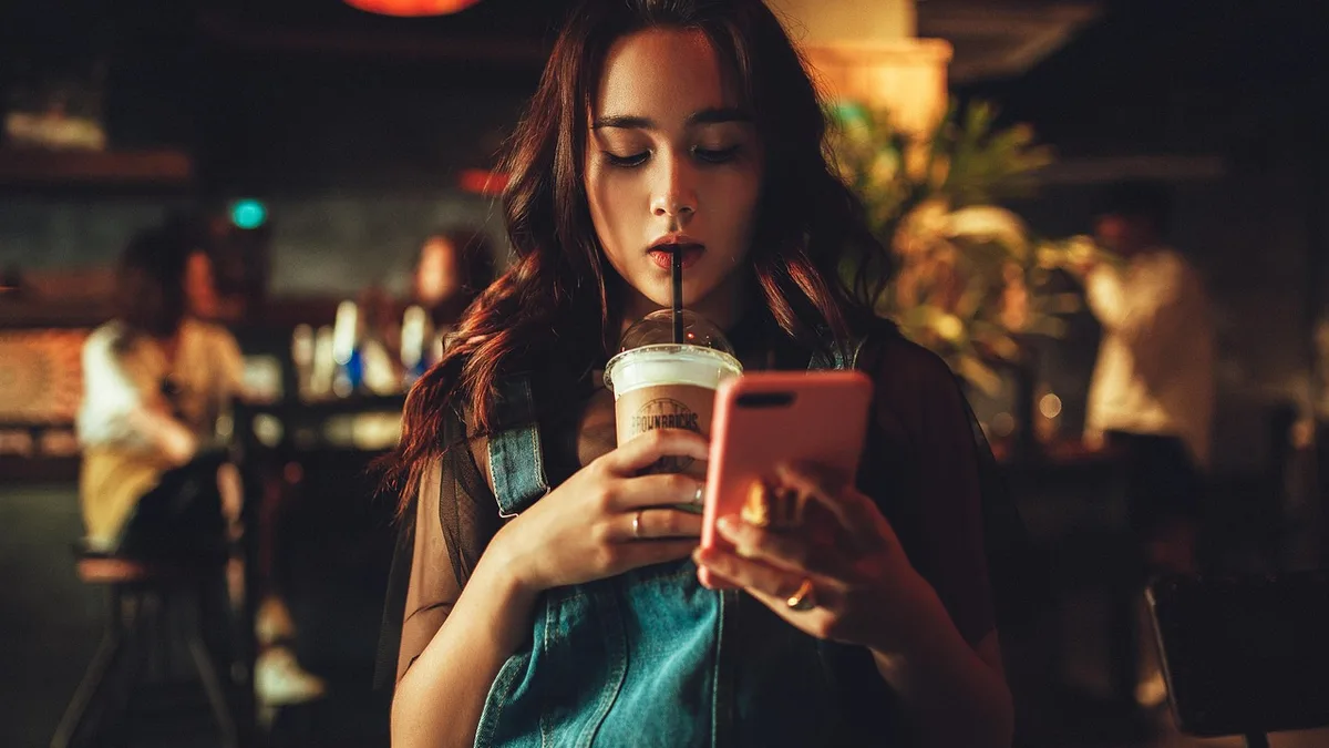 Kafede telefon ekranına bakan kişi