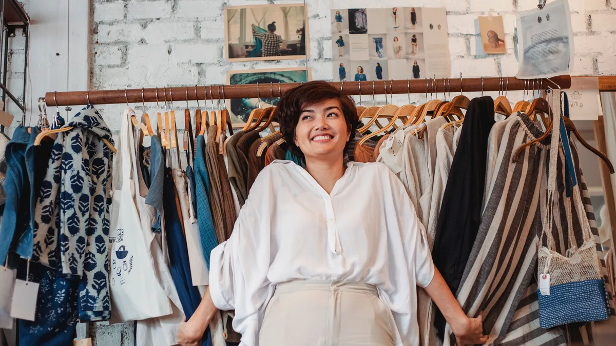 Giysi askılarının önünde oturan butik sahibi