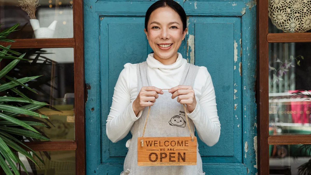 Kafe kapısında açık tabelası tutan çalışan