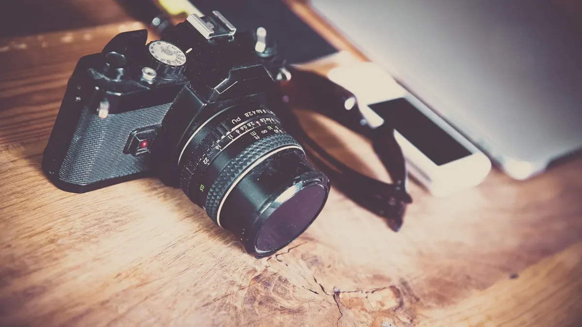 Ahşap masa üzerinde fotoğraf makinesi ve dizüstü bilgisayar