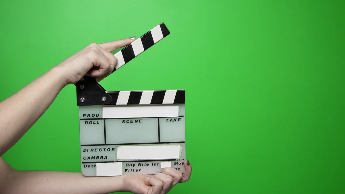 Yeşil fon önünde film klaketi tutan el