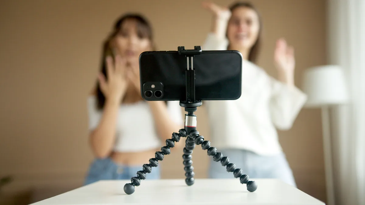 Tripod üzerindeki telefon karşısında video anlatan iki kadın