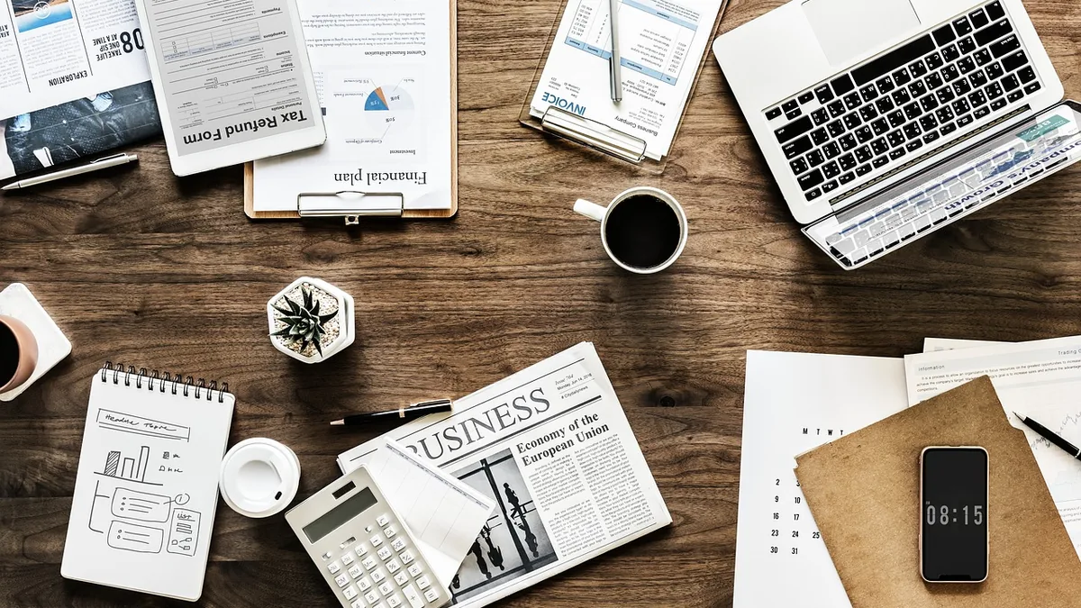 Planlama belgeleri, dizüstü bilgisayar, telefon ve not defteri bulunan çalışma masası