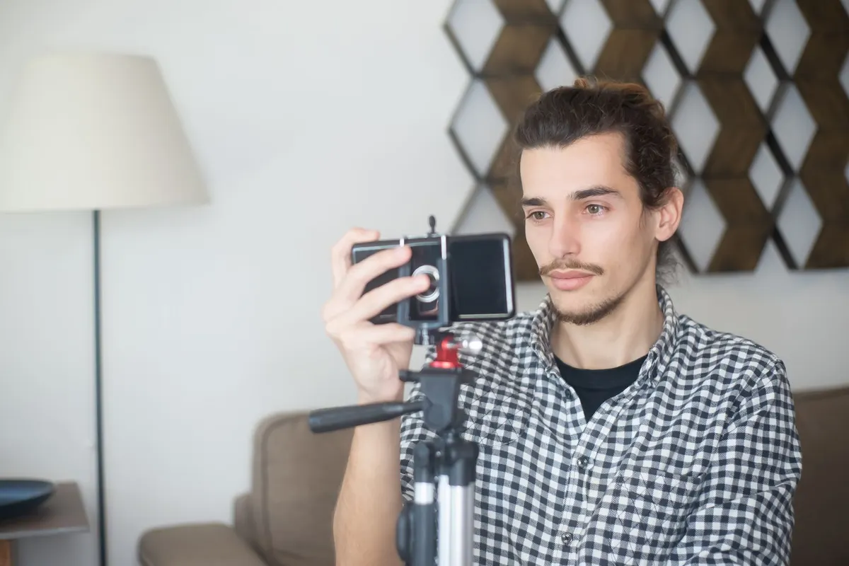 Tripoda takılı telefonuyla vlog videosu çeken bir içerik üreticisi