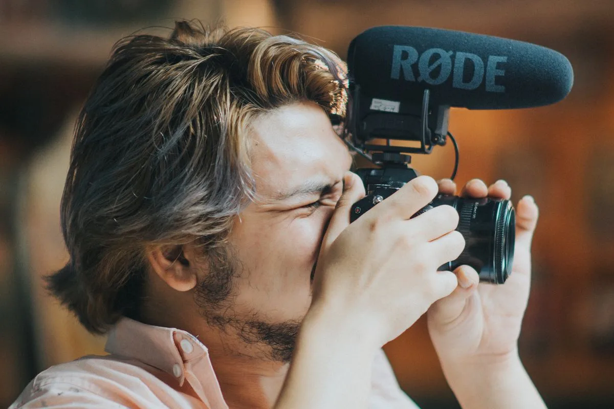 Elindeki fotoğraf makinesiyle çekim yapan bir içerik üreticisi