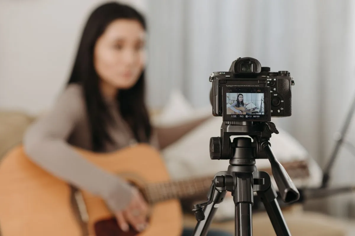 Kamera karşısında gitar çalarak kayıt yapan bir kadın