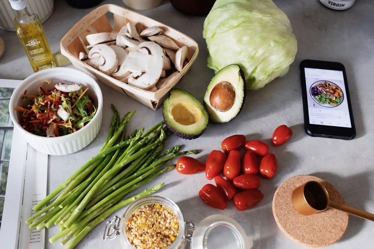 Kuşkonmaz, avokado, domates ve mantar gibi sağlıklı yemek malzemelerinin yanında duran telefon