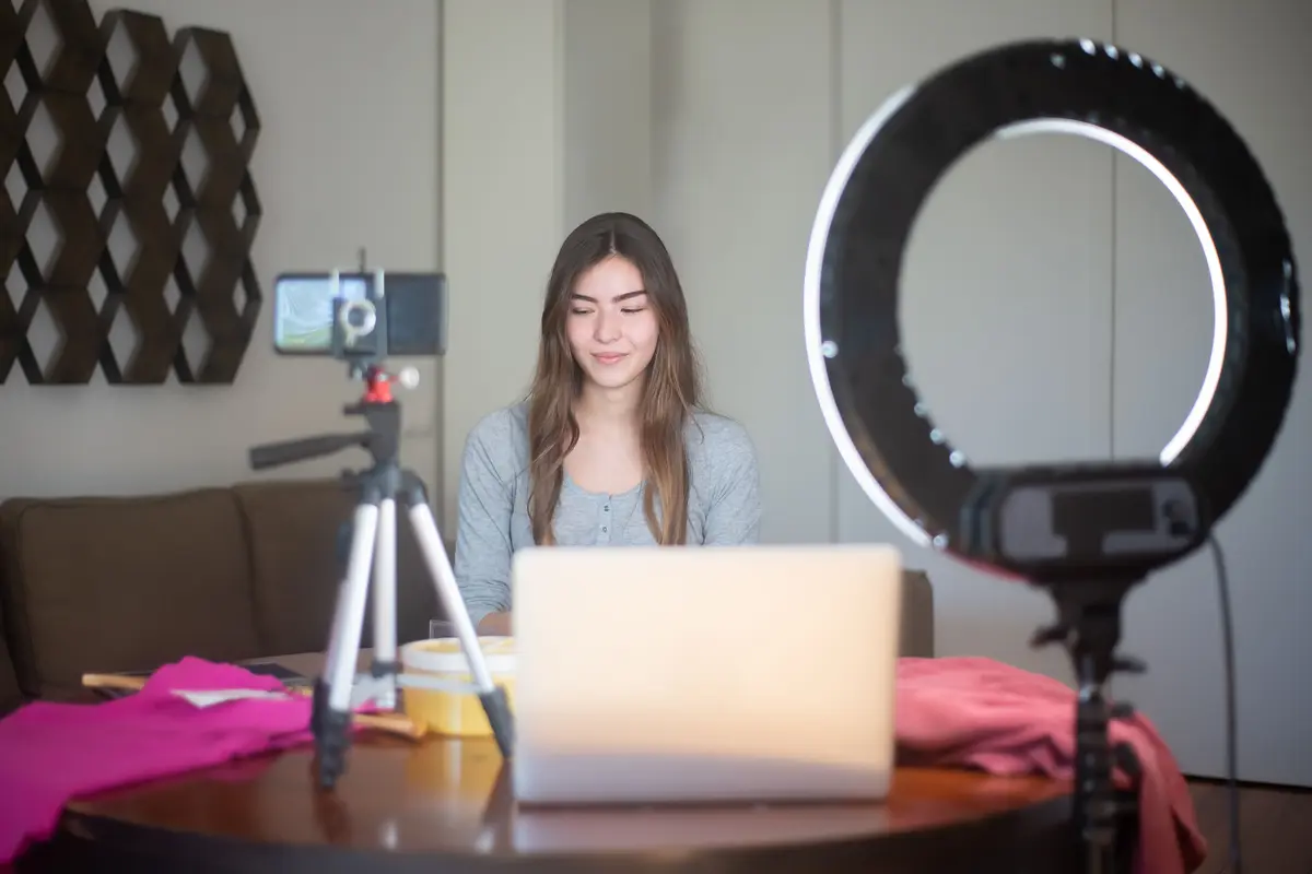 Halka ışık ve tripod bulunan çalışma alanında içerik çekimine hazırlanan kadın