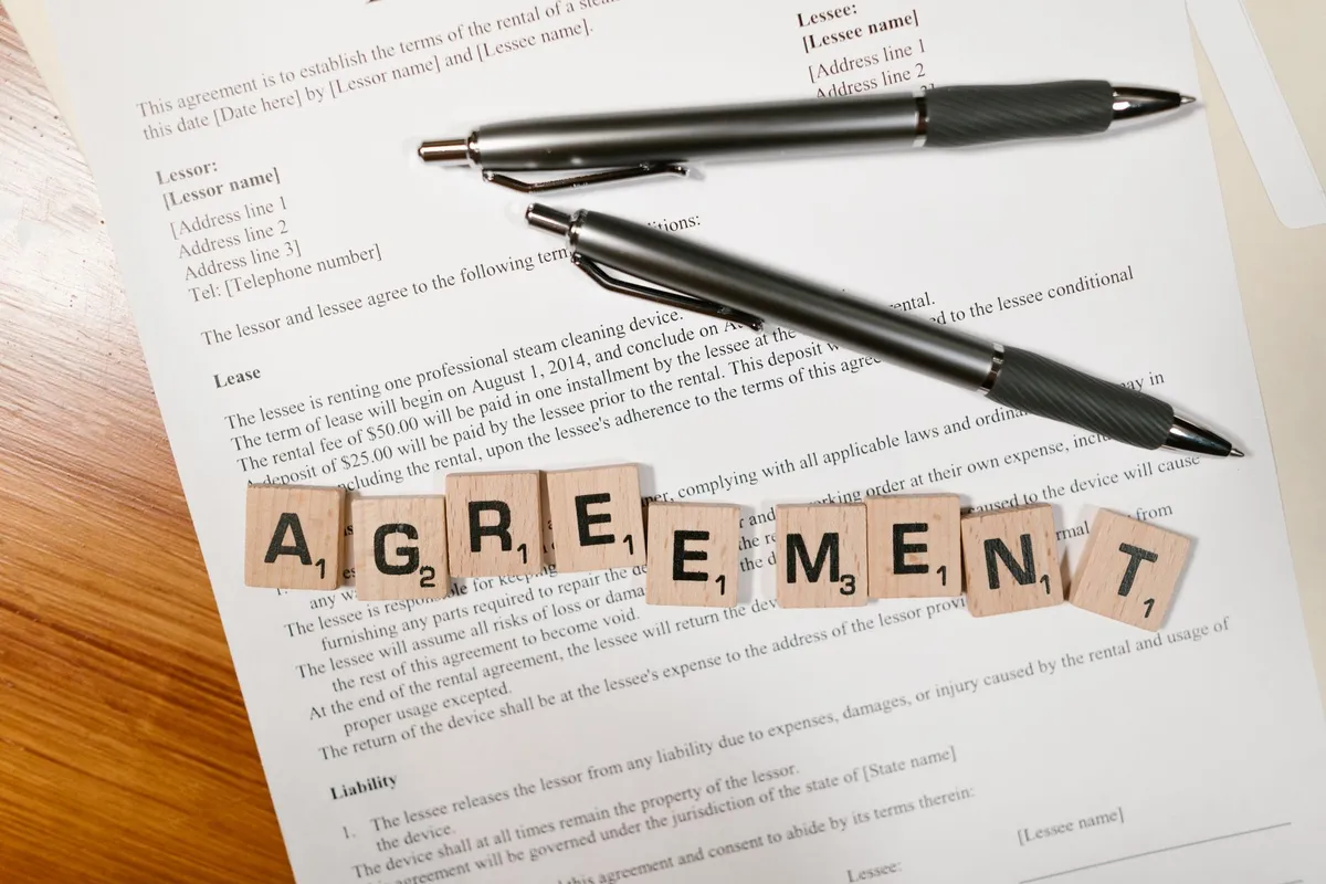 Sözleşme metni üzerinde AGREEMENT harfleri ve kalemler