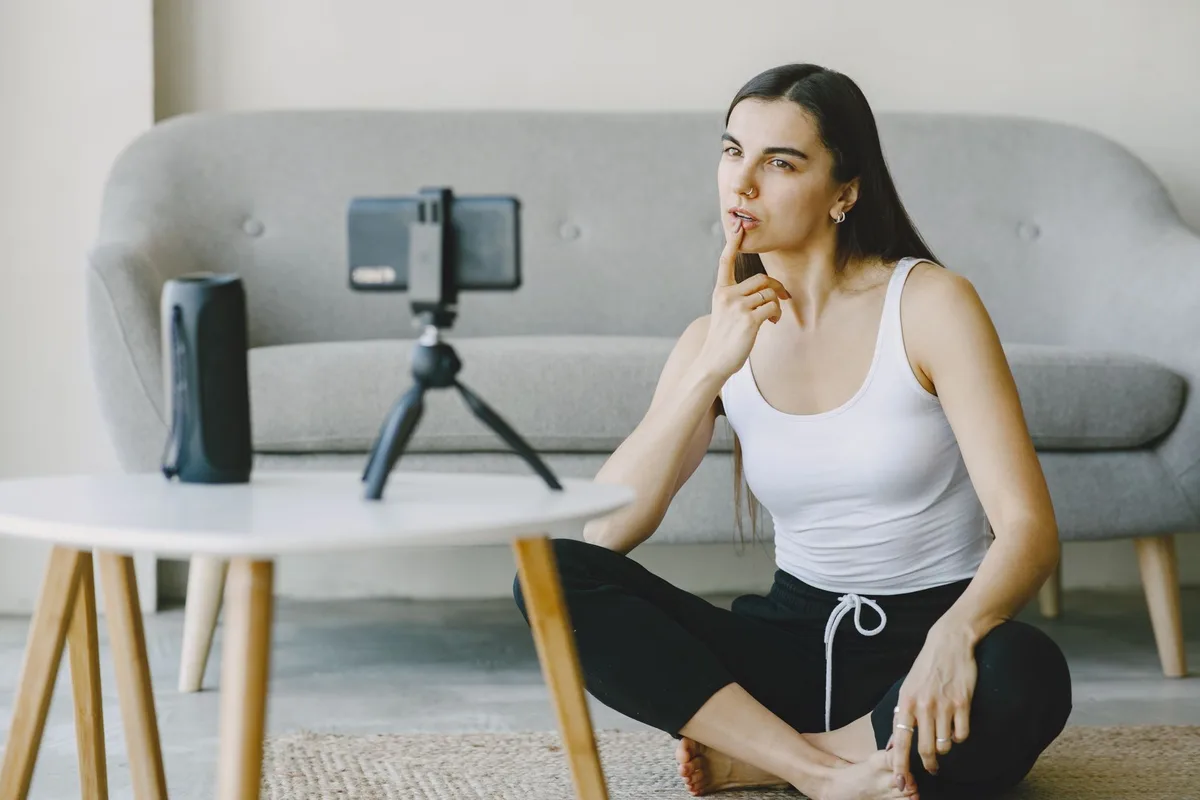 Tripod üzerindeki telefonla evde video kaydeden kadın