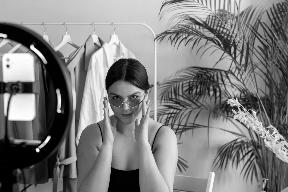 Telefon ve kamera önünde moda içeriği hazırlayan kadın