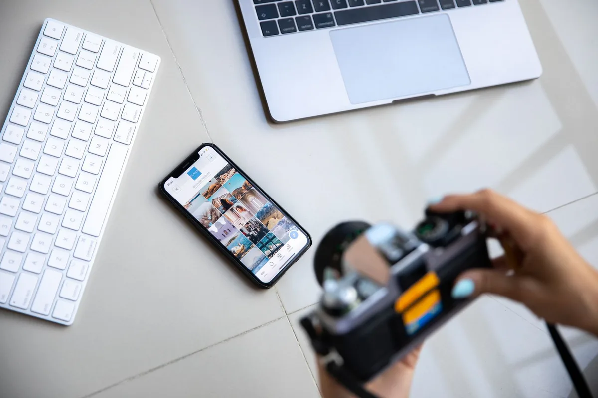 Bilgisayar ve telefon yanında cihaz fotoğrafı çeken kişi