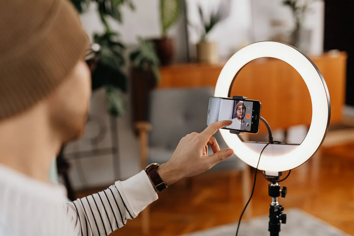 Halka ışık önünde telefonla video çeken kişi