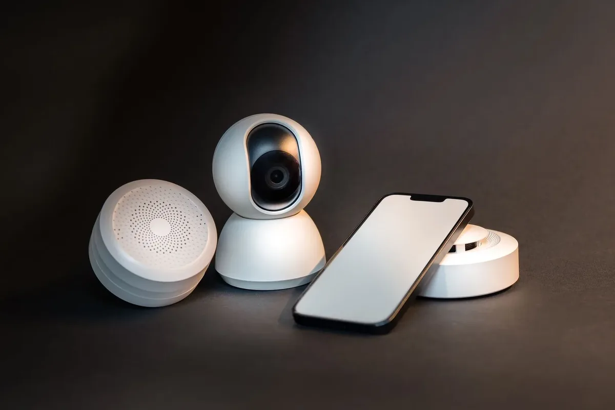 Gri zeminde akıllı telefon, kamera ve ev sensörleri
