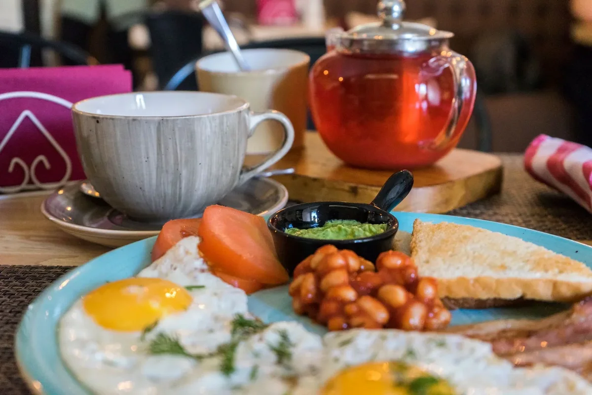 Çay, kahvaltı tabağı ve fincan bulunan restoran masası