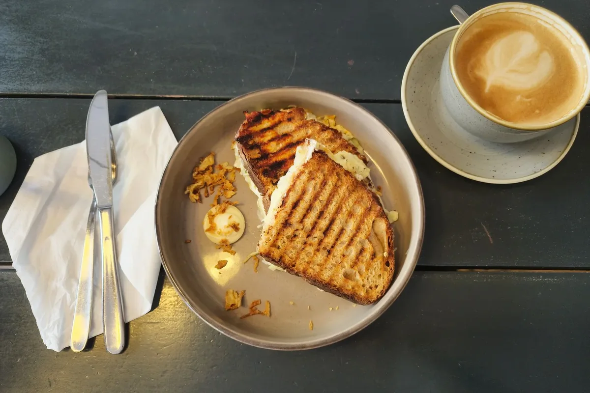 Kafede tost, kahve ve çatal bıçak bulunan masa